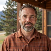 Daniel, a 56-year-old Dremeet member from Colorado, smiling on a mountain cabin porch in a rust flannel shirt