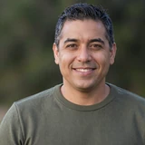 Michael, a 54-year-old Latino Dremeet member from Pennsylvania, smiling confidently in olive green