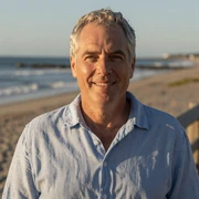 Richard, a 60-year-old widowed Dremeet member from Florida, smiling in a blue linen shirt on a coastal boardwalk