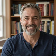Robert, a 58-year-old Dremeet member from Ohio, smiling in a navy henley shirt in his home study